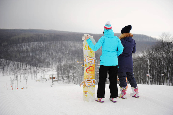 Kaksi tyttöä lumilaudat seisoo päälle yksivärinen tausta talvi maisema
 - Valokuva, kuva