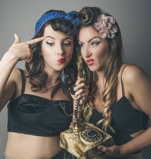 Két fiatal nő grimaszok retro telefon - Fotó, kép
