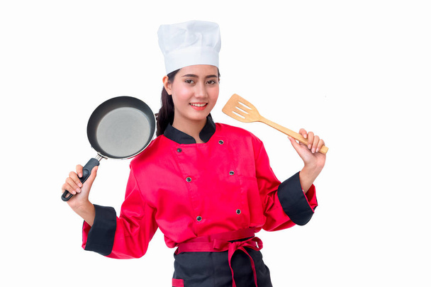 Lachende vrouw van de chef-kok in het rode uniform holding kookgerei - Foto, afbeelding