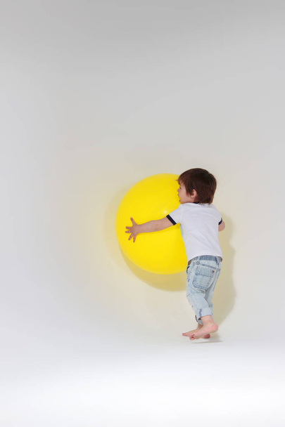 Little boy playing with a big yellow ball. - Foto, Imagen