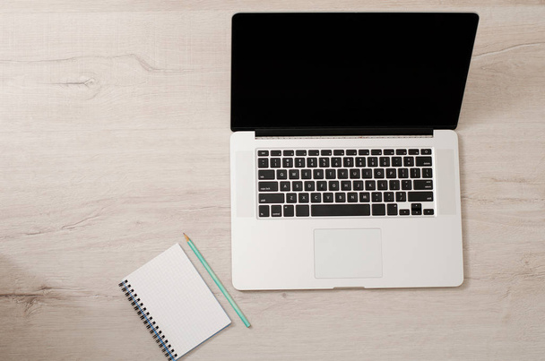 Top view of a laptop and a notebook with a pencil on a light wooden background,  space for text - Photo, Image