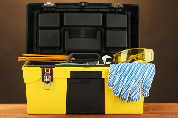 Open yellow tool box with tools on brown background close-up - Φωτογραφία, εικόνα
