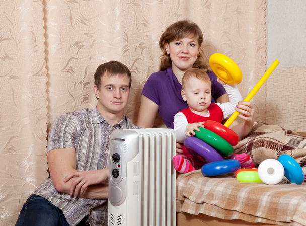 parents and child near warm radiator - Foto, afbeelding