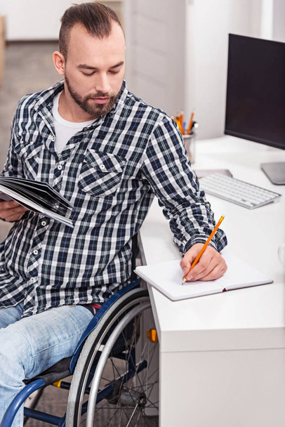 Handsome handicapped man taking notes - Foto, afbeelding