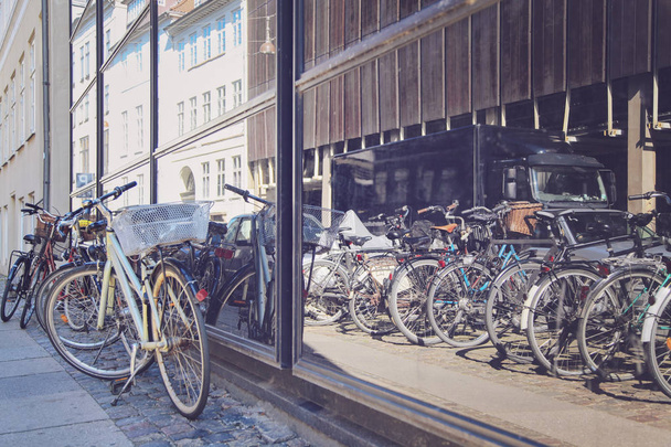 Велосипеды на улице рядом с витриной магазина в Копенгагене, Дания
 - Фото, изображение