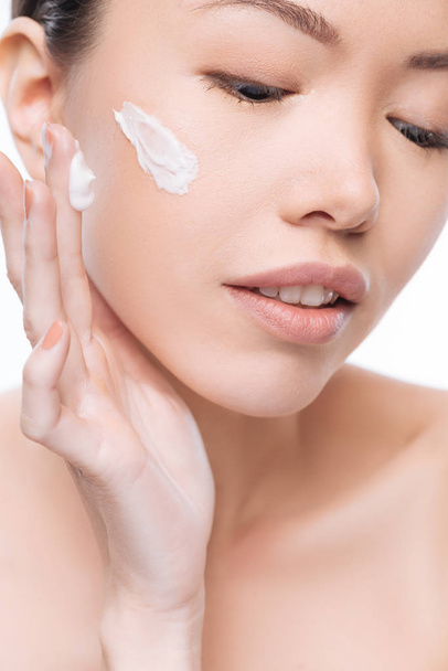 Beautiful positive woman applying cream on her face - Foto, imagen