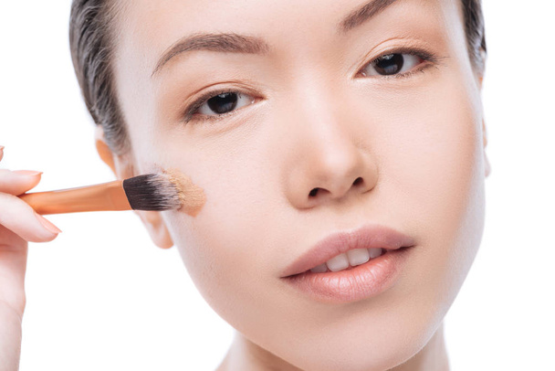 Pretty good looking woman using a cosmetic brush - Photo, image