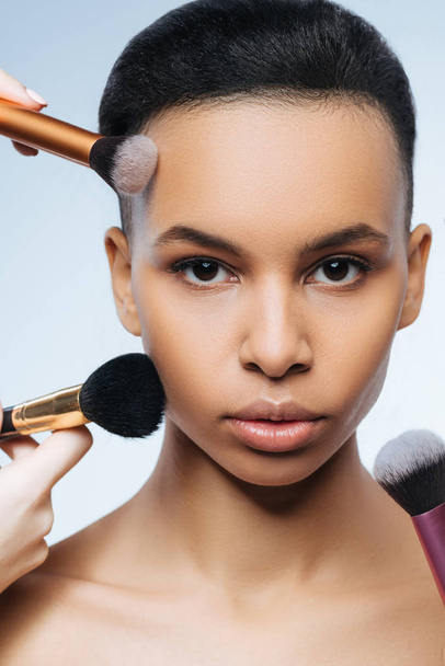 Beautiful cute woman being surrounded by makeup brushes - Photo, image