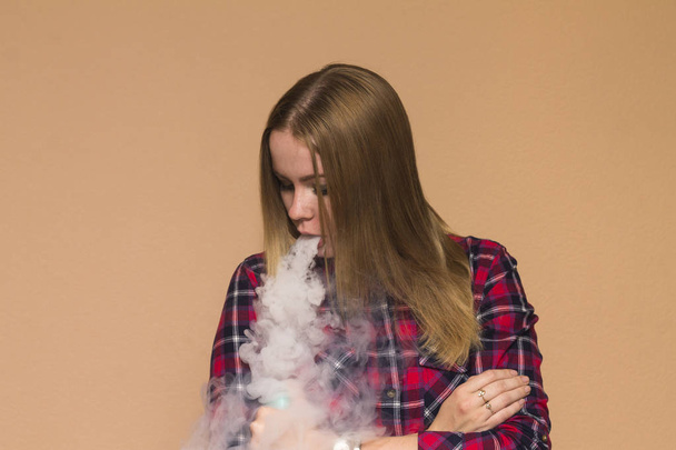 Vape dziewczyna w czerwonej koszuli palenia papierosów elektronicznych - Zdjęcie, obraz