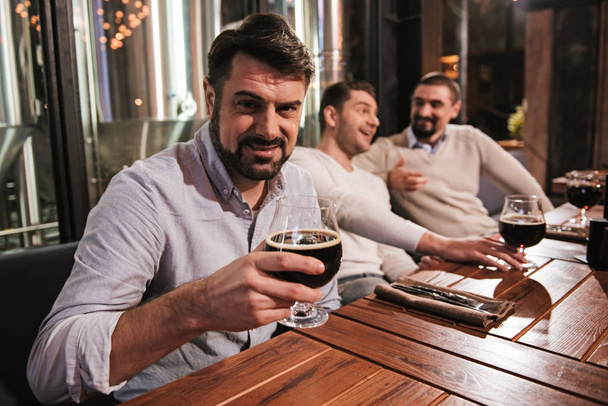 Handsome bearded man holding a glass with beer - 写真・画像