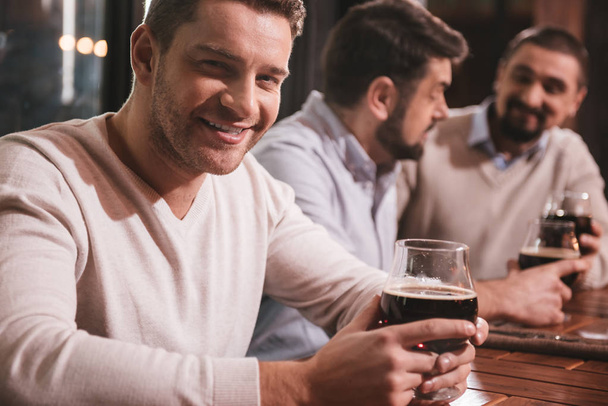 Attractive smiling man sitting with his friends at the table - Photo, Image