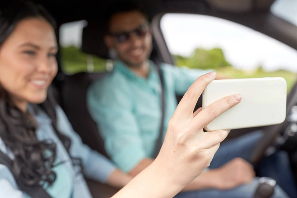 couple driving in car and taking smartphone selfie - Foto, Imagen