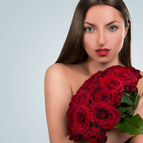 Portrait of a beautiful young woman with a big bouquet of flowers - Foto, afbeelding