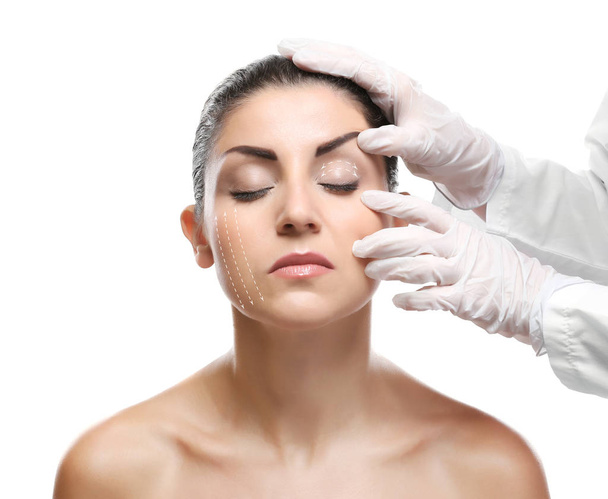 Plastic surgery concept. Doctor examining female face, white background - Fotó, kép