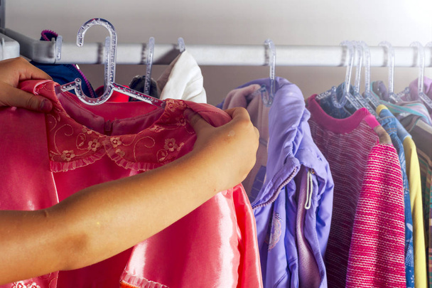 Dziecko dziewczynka wybierając ubrania do noszenia w szafie. - Zdjęcie, obraz