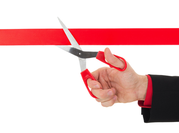 Рука людини ріже червону стрічку ножицями
 - Фото, зображення