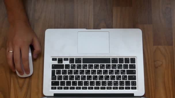 Una mano jugando al ratón ante un teclado plateado acostado sobre una mesa
. - Metraje, vídeo