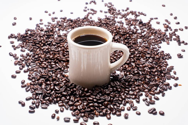 Φλιτζάνι καφέ με μαύρο περιβάλλεται από κόκκους καφέ. - Φωτογραφία, εικόνα