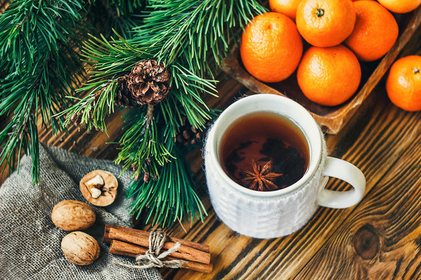 Christmas New Year composition winter holiday celebration concept symbol tangerines clementine nuts pine cones fir branches cup tea rustic style old wooden board selective focus festive greeting card - Photo, Image