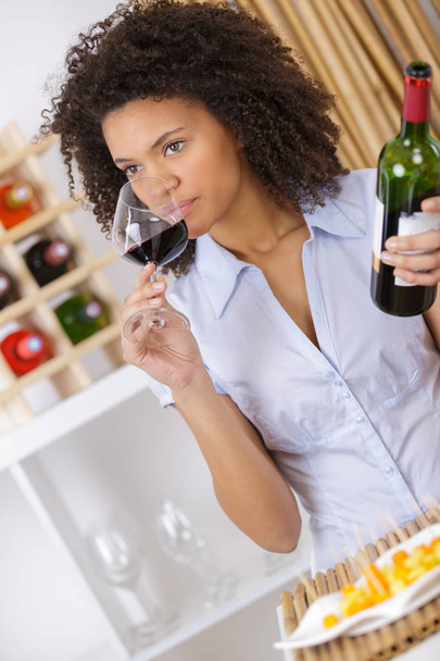 woman tasting wine in glass and holding bottle - Zdjęcie, obraz