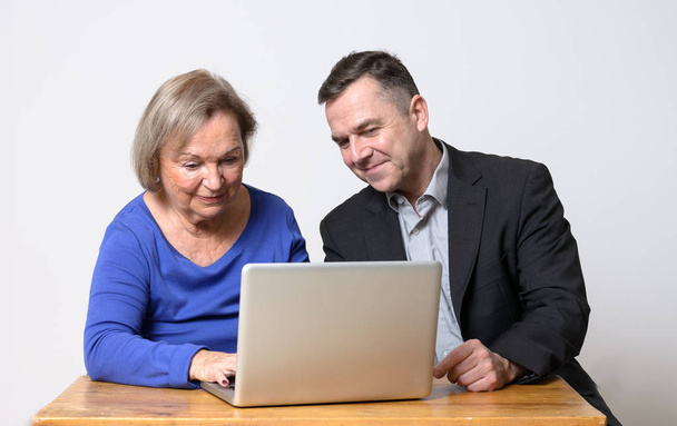 Senior woman using computer beside man in suit - Photo, Image