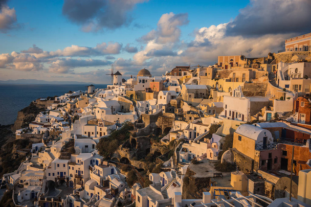 White city on a slope of a hill at sunset, Oia, Santorini, Greec - Foto, Bild