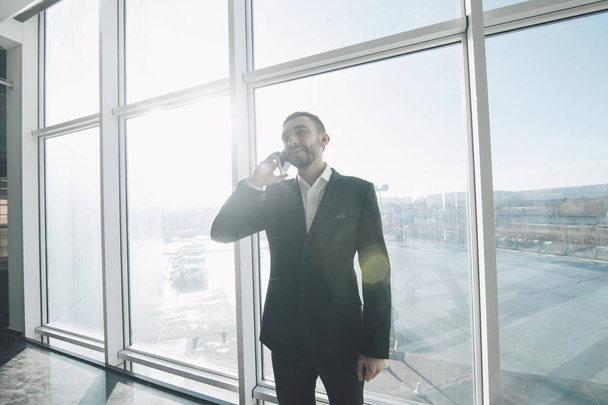 Handsome businessman in suit speaking on the phone in office - Foto, Bild