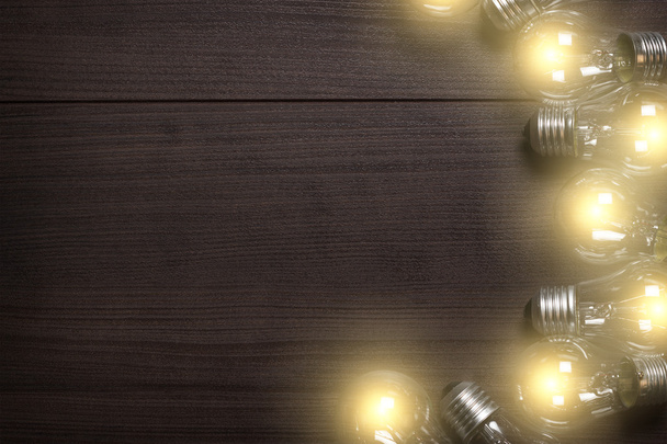 Glowing bulbs over wooden background - Valokuva, kuva