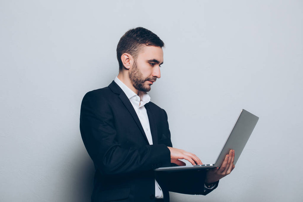 Νεαρός επιχειρηματίας στο κοστούμι με φορητό υπολογιστή στα χέρια - Φωτογραφία, εικόνα
