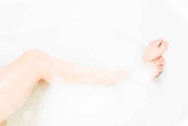  Women's slender legs in a bath with fragrant foam - Valokuva, kuva