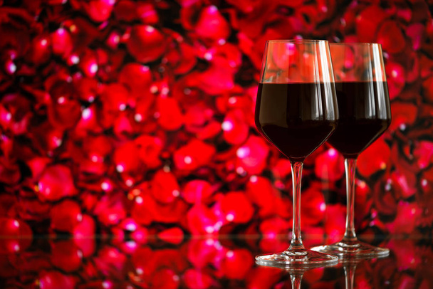 Two glasses of red wine against bokeh background with sparkles and roses. Very shallow depth of field. Selective focus, copy space - Photo, Image