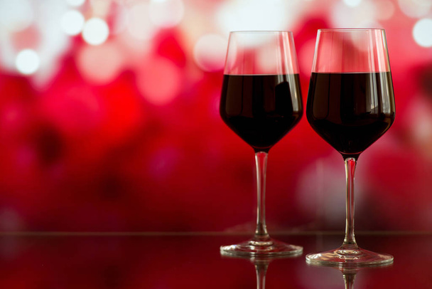Dvě skleničky červeného vína na pozadí bokeh se leskne a růží. Velmi malá hloubka ostrosti. Selektivní fokus, kopie prostor - Fotografie, Obrázek