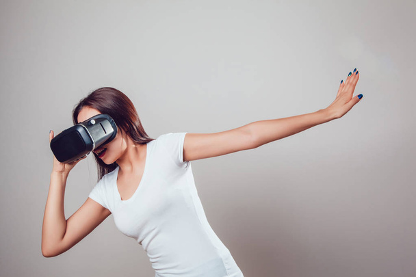 Aantrekkelijke vrouw met behulp van virtual reality bril op grijze achtergrond. Vr headset. - Foto, afbeelding