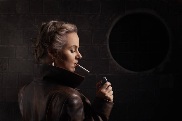 Kobieta w brązowy skórzany płaszcz z zapalniczki i papierosów - Zdjęcie, obraz