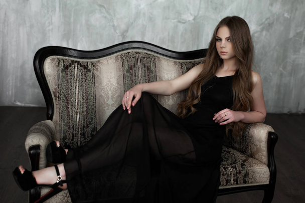 junges Mädchen mit langen, schönen Haaren und rauchigen Augen im schwarzen Maxi-Abendkleid. Studioaufnahme - Foto, Bild