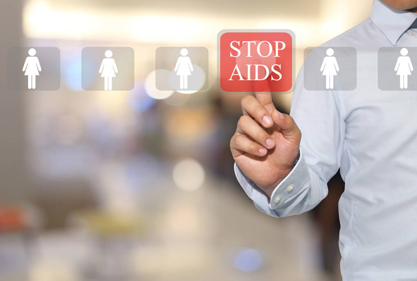 Hand of businessman touch text in STOP AIDS on Hospital blurred  - Photo, Image