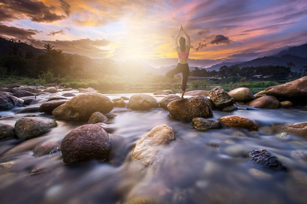 Mujer joven haciendo yoga en la roca en la mañana
 - Foto, Imagen