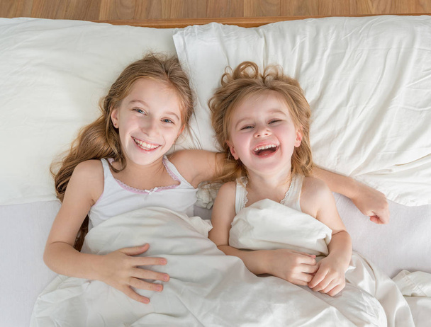two little lovely sisters in white bed - Foto, Bild
