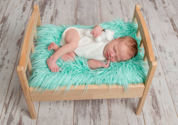 beautiful sleeping baby on wooden cot with turquoise blanket - Photo, image