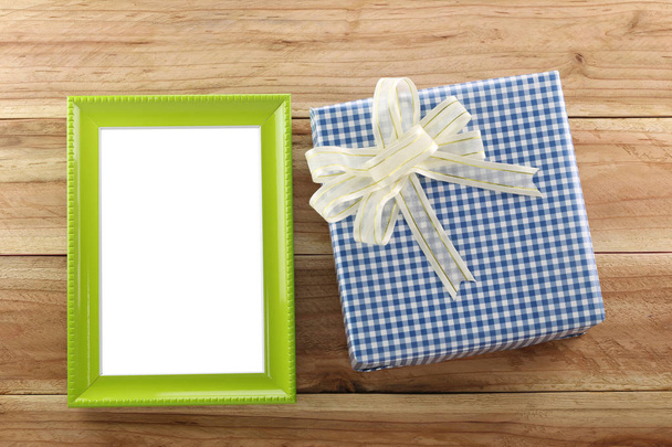 Caja de regalo azul lugar cerca de marco de madera verde en el suelo de madera
. - Foto, imagen