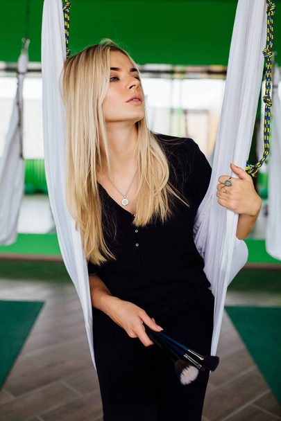Portrait of a cute beautiful girl mekeup artist natural with long hair blond. In the studio, anti gravity fitness yoga . - Photo, Image