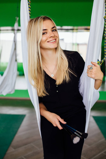 Portrait of a cute beautiful girl mekeup artist natural with long hair blond. In the studio, anti gravity fitness yoga . - Photo, image