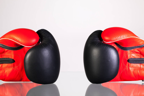Red and black boxing gloves on a glass table  - Fotografie, Obrázek