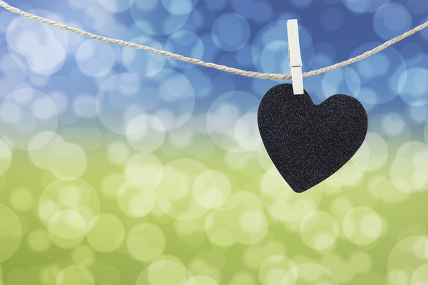 Black Heart opgehangen aan hennep touw op abstract kleurrijk bokeh backgro - Foto, afbeelding