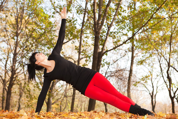 Pretty woman doing sport exercises in the autumn park - Фото, зображення
