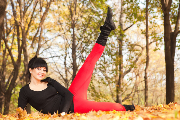 Pretty woman doing sport exercises in the autumn park - Photo, image
