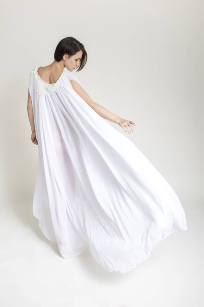 schlanke Passform kaukasische brünette Frau in weißem langen Kleid im Studio. - Foto, Bild