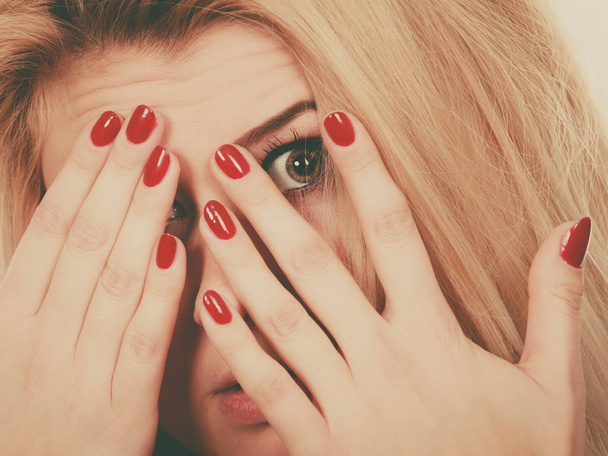Woman covering face with hands showing red nails - Foto, Imagen