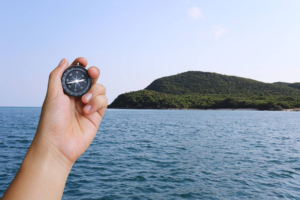 Hand of man holding a compass and sea island view. - Φωτογραφία, εικόνα