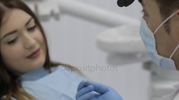 Dentist talking with patient and showing a model of teeth. - Filmati, video